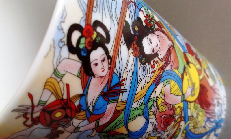 an artistic vase with images and details painted on it