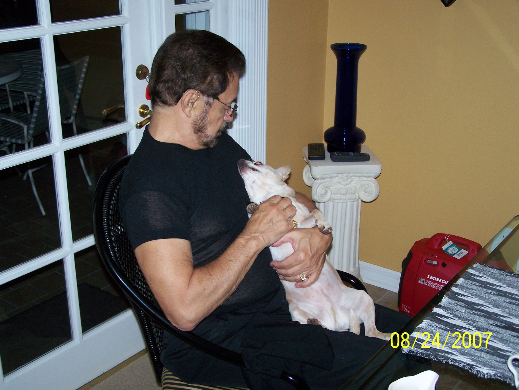 a man sits on his laptop while holding a small dog