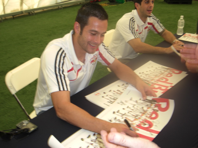 two men sitting at a table signing autographs