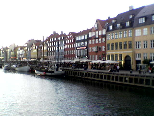 people are walking by the water near some buildings
