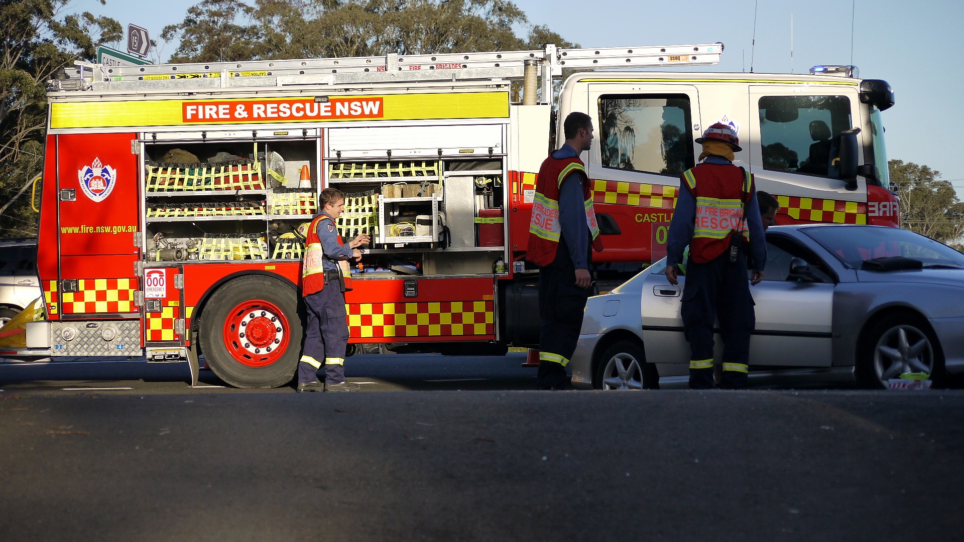 two fire and rescue employees standing near a white car