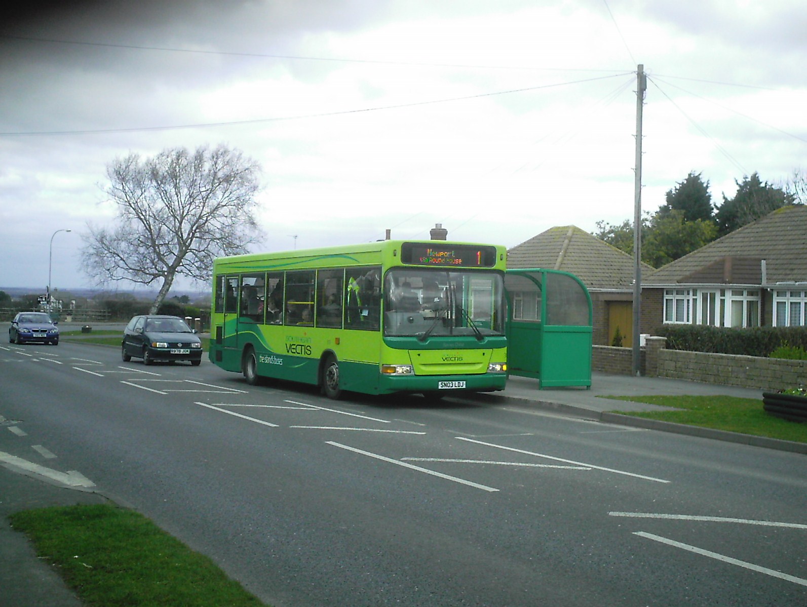 a green bus is stopped on the side of a road