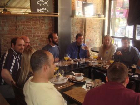 many people are sitting at a table eating food and talking