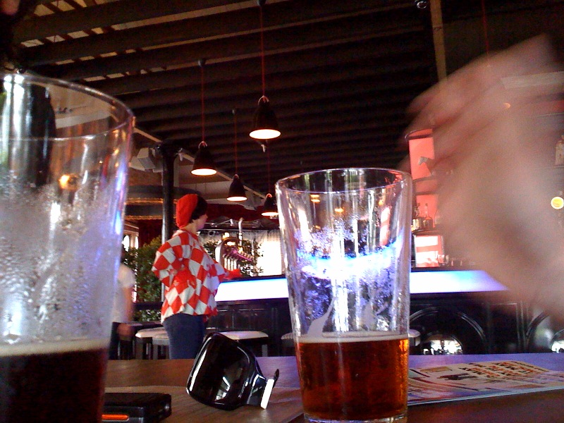 a glass of beer sitting on top of a wooden table