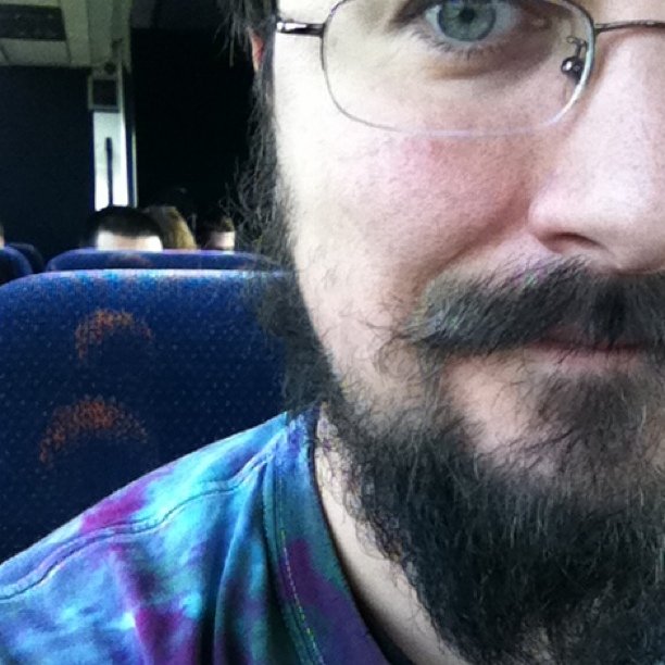 a man wearing a tie dye shirt with a beard and glasses