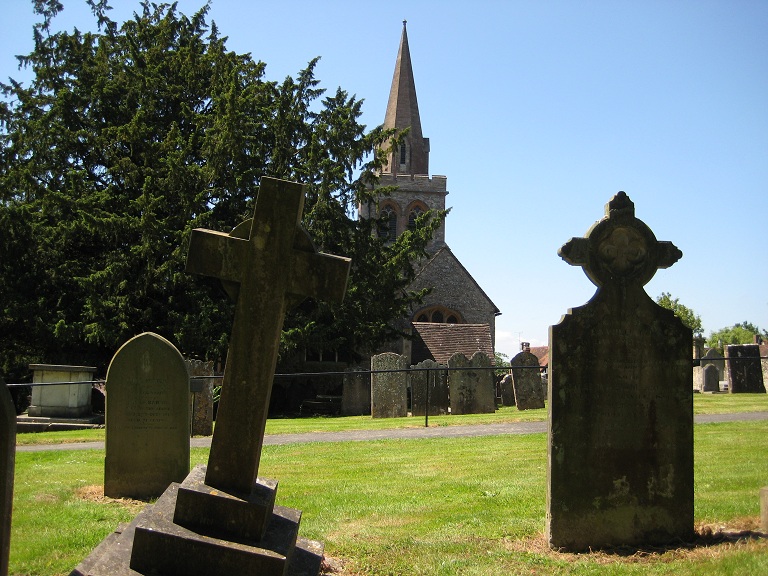 a cemetery with a tower and crosses with trees in the background