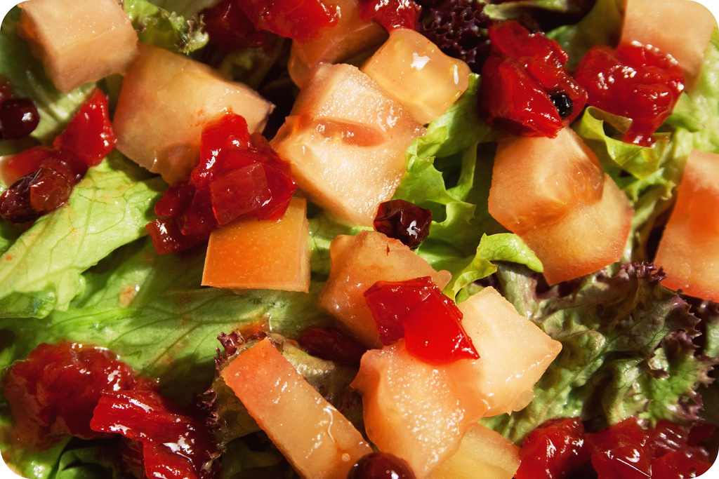 many pieces of fruit and leaves on a green salad