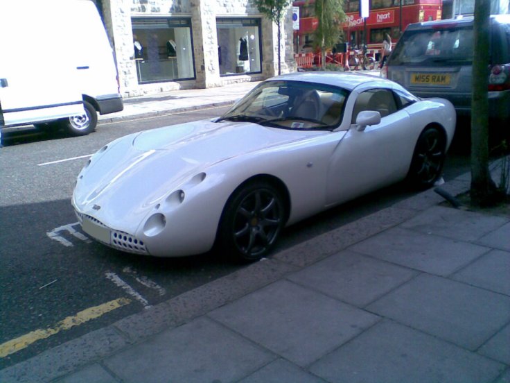 a white sports car sitting on the side of a road next to a curb