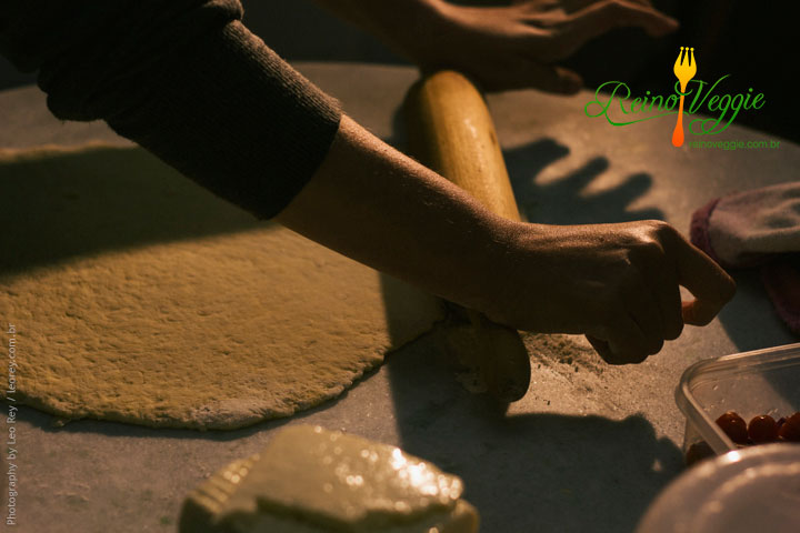 a hand rolling dough into some pizza dough