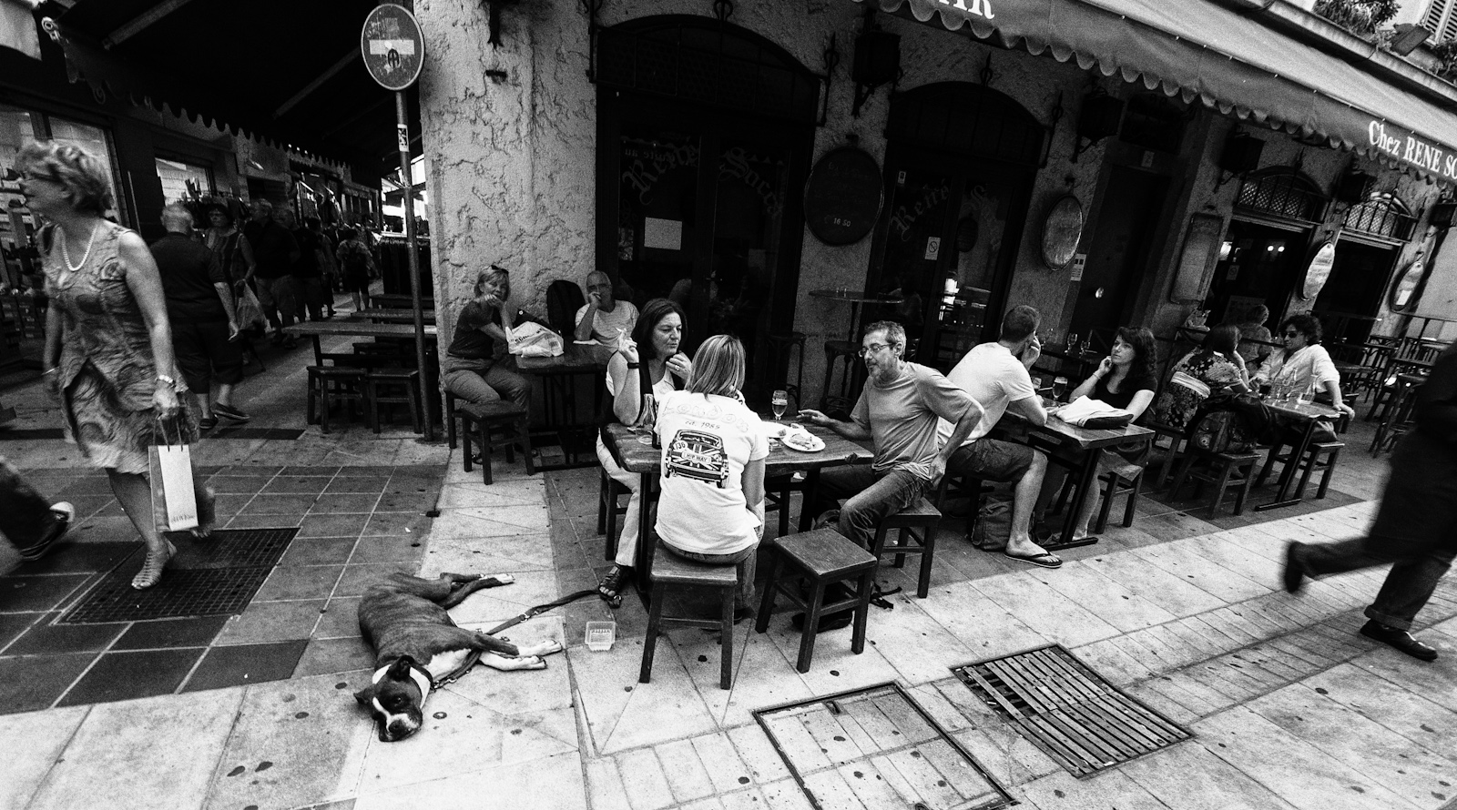 people sitting at tables outside of an outdoor restaurant