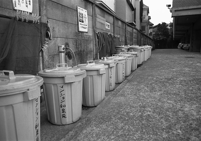 a row of trash cans along the side of a building