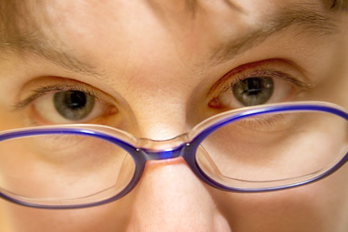 a young person with blue rimmed glasses has a frown