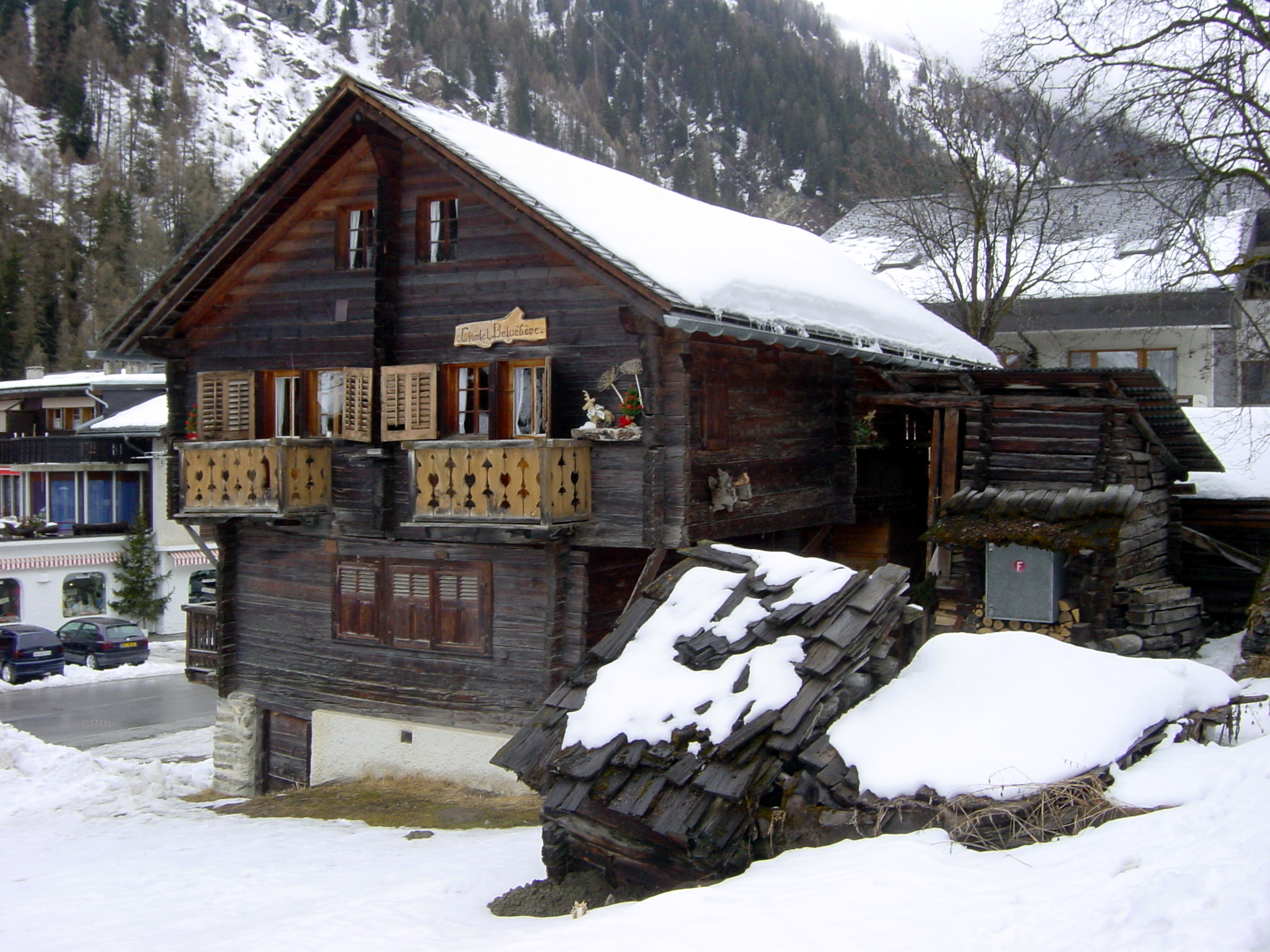 a snow covered log cabin at the foot of a snowy mountain