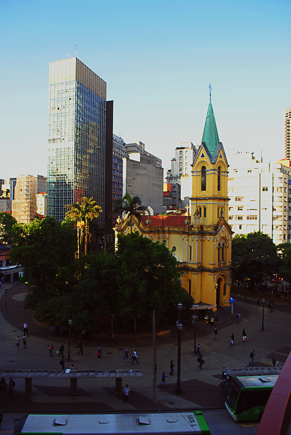 a tall yellow church building sitting in the middle of a city