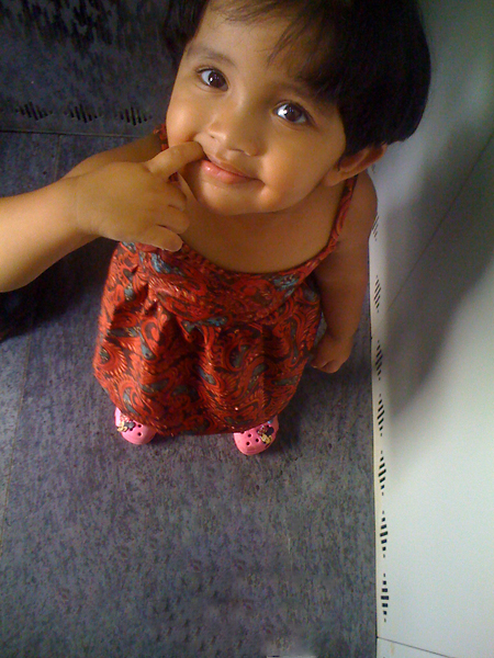 a little girl wearing an orange dress sitting on a floor