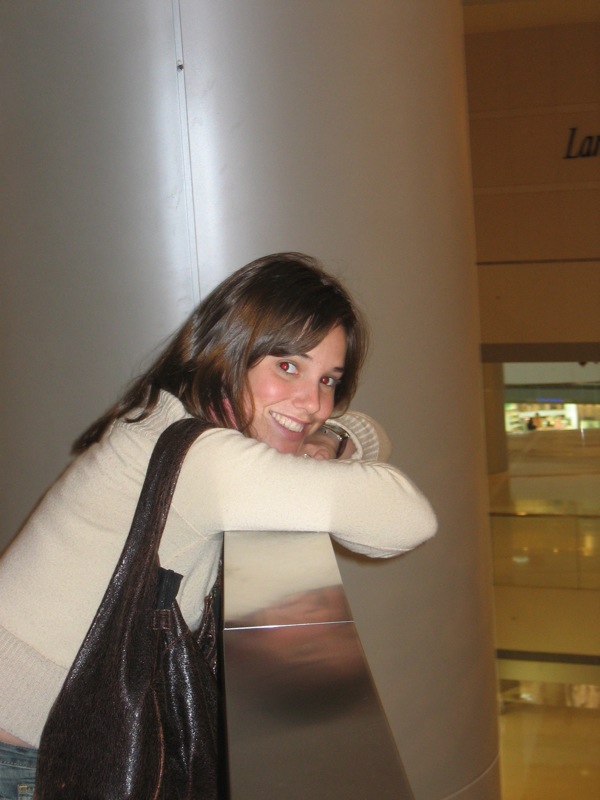 a woman is smiling at the camera while standing near a large round wall