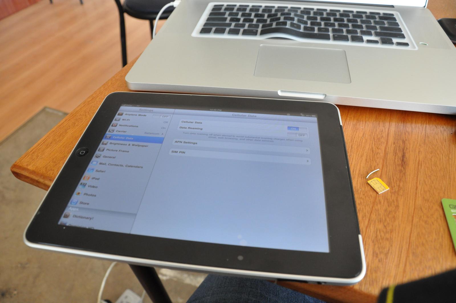 a tablet sitting next to a laptop on a wooden desk