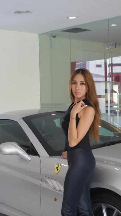 woman posing in front of car in a showroom