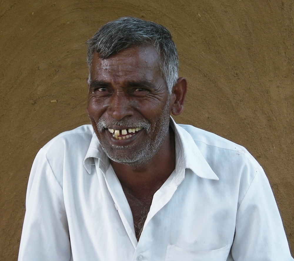 a close - up of a man smiling wearing a white shirt