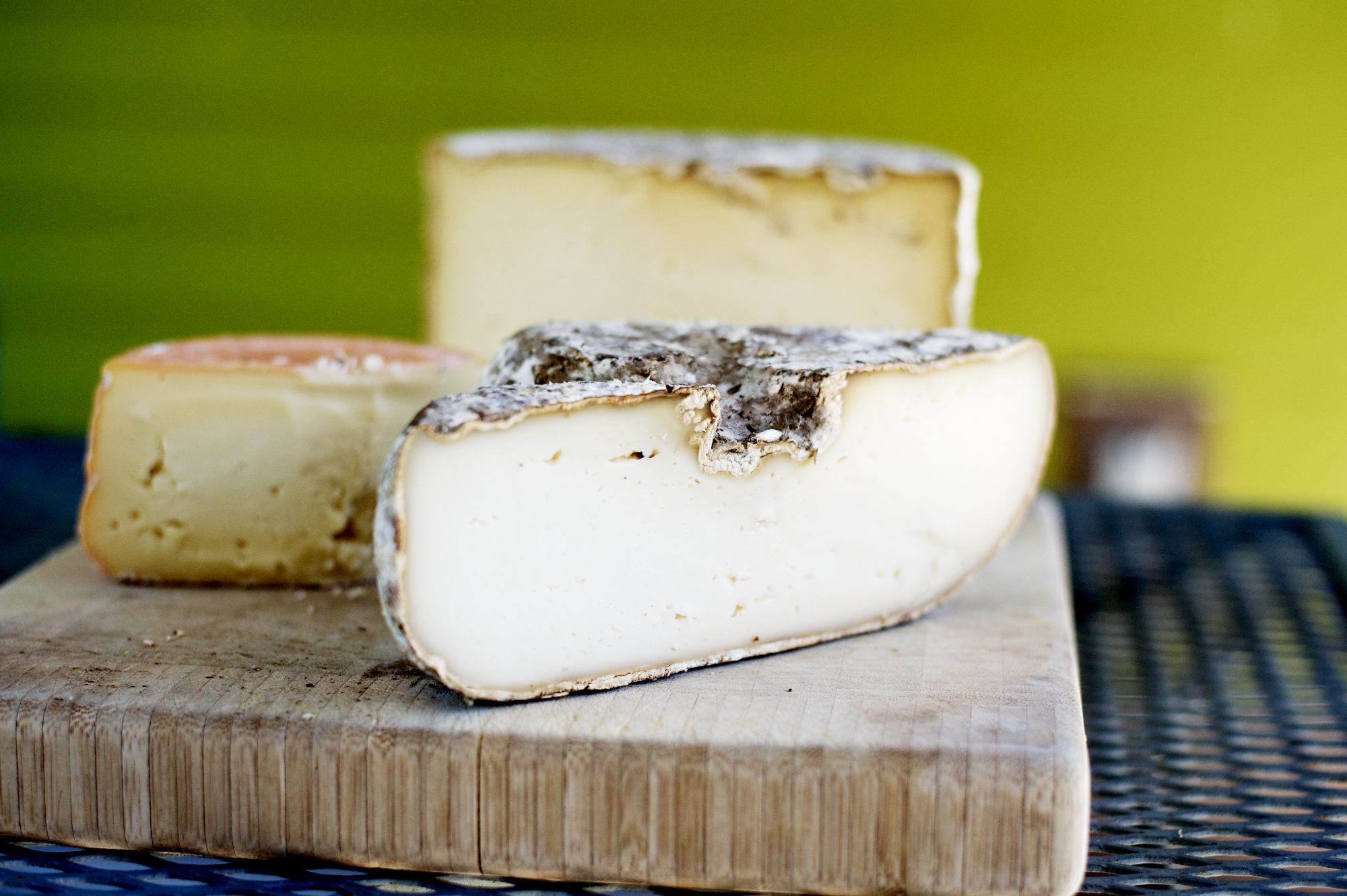 pieces of cheese sitting on a wooden  board