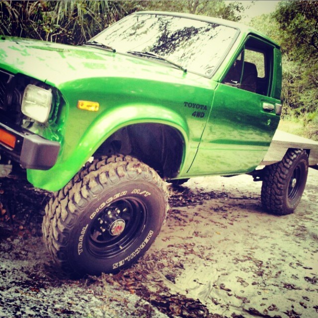 a green pick up truck parked in a forest