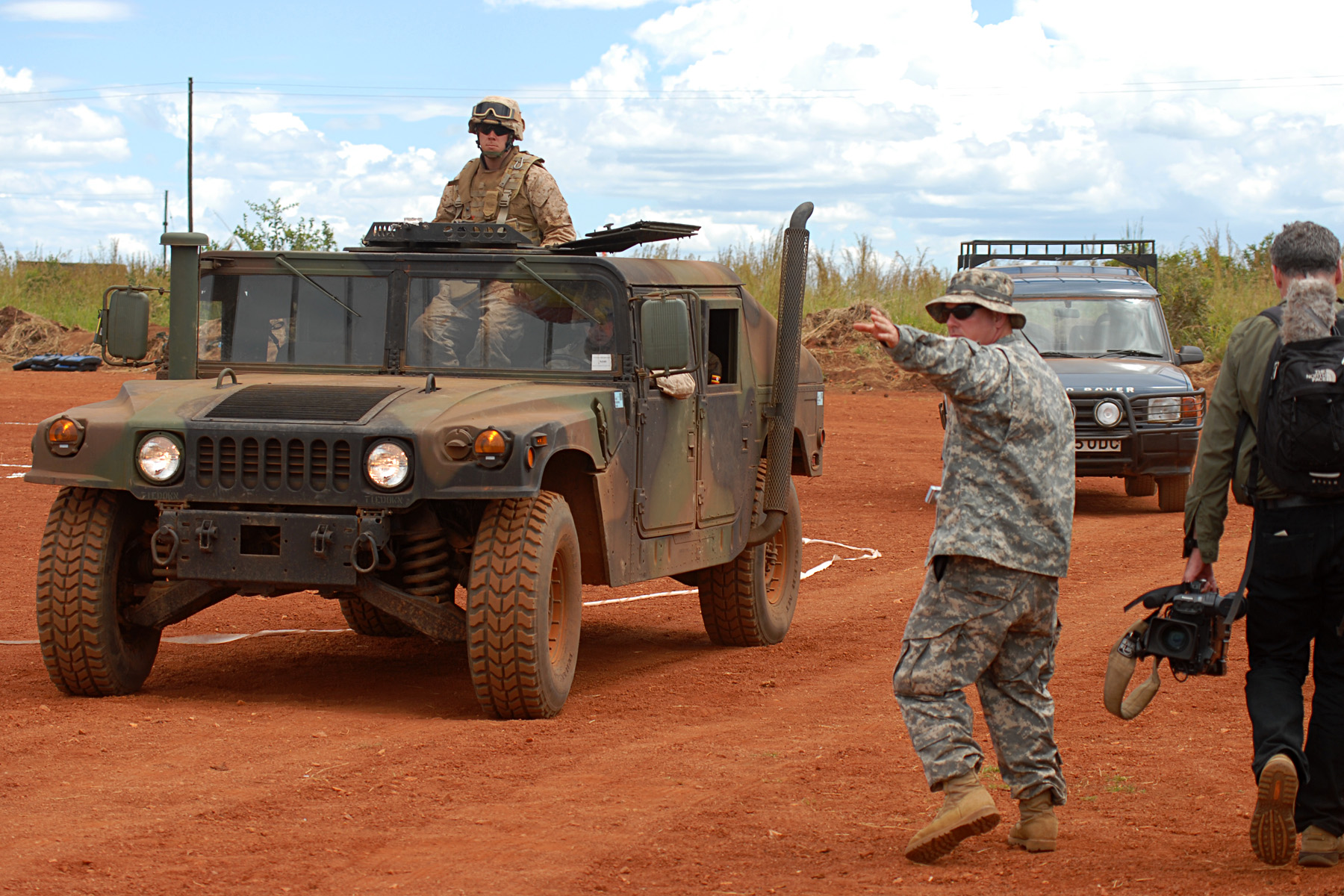 two soldiers walking by an army truck and a jeep