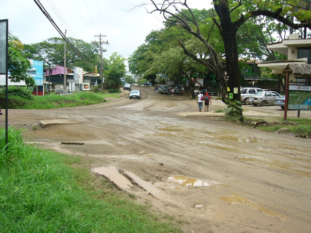 two people walking on dirt road surrounded by cars