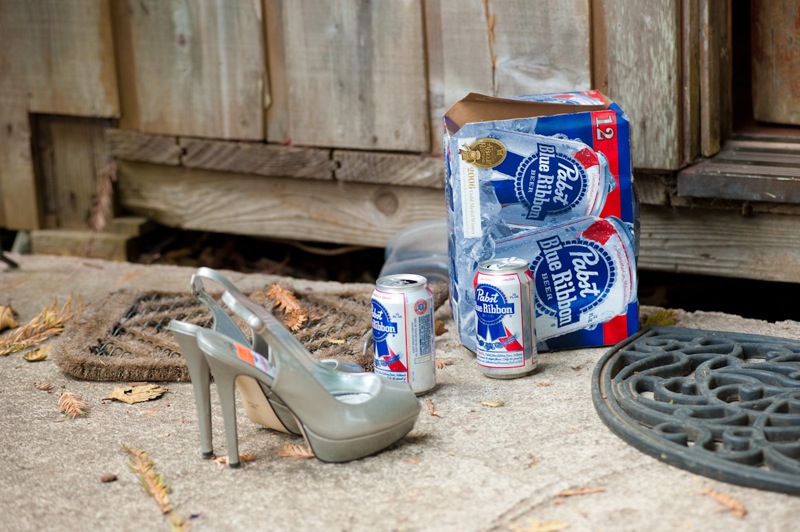 a pair of high heeled sandals, a box of corona beer and a heel - shaped shoe sitting on the concrete