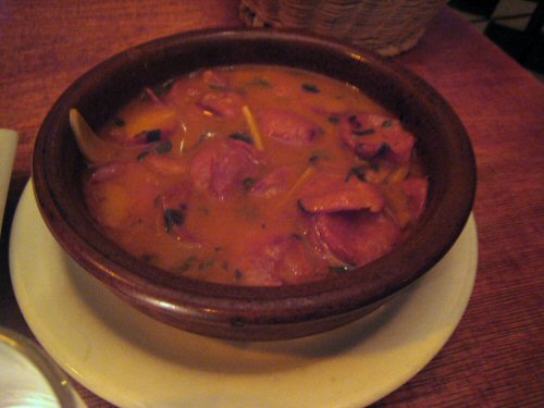 a bowl of food with soup and silverware on a plate