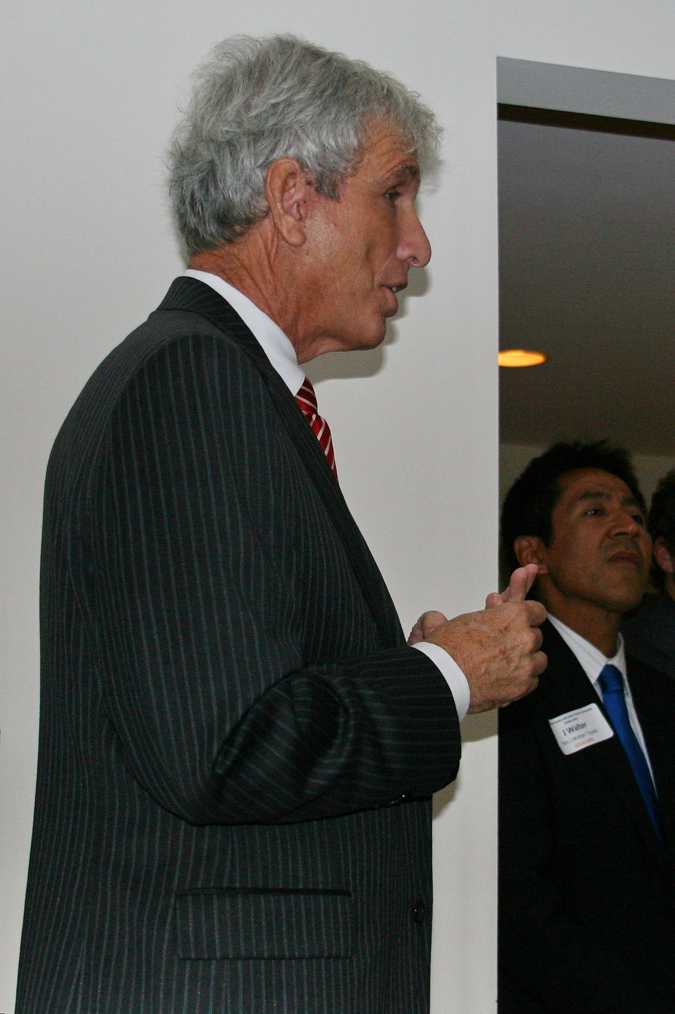 a man wearing a suit talking into another person's ear