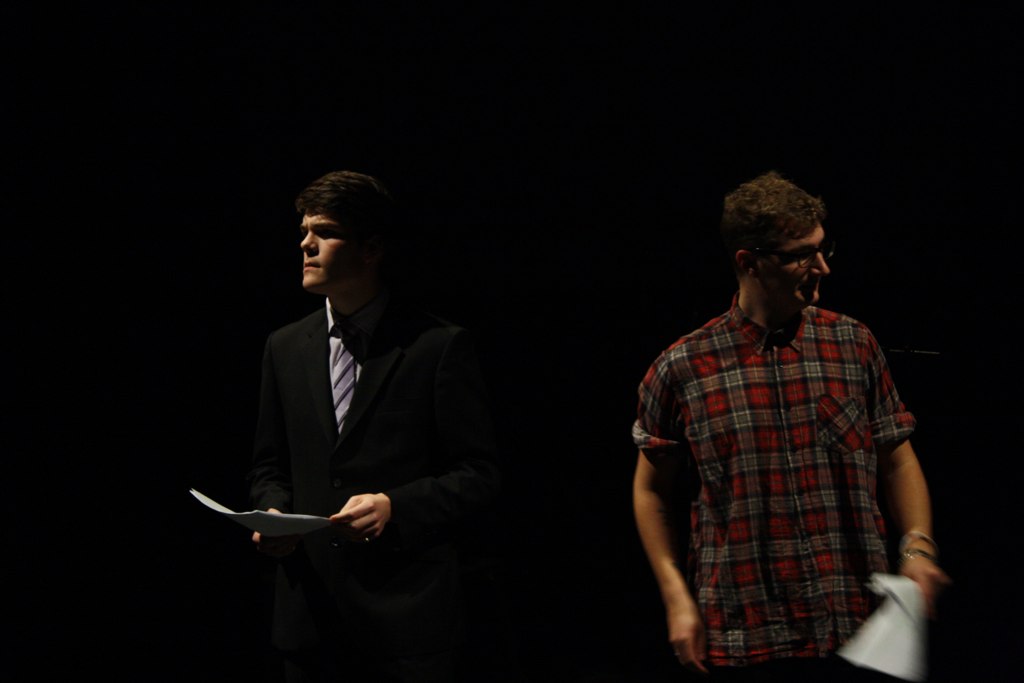 two men in business attire are talking on stage