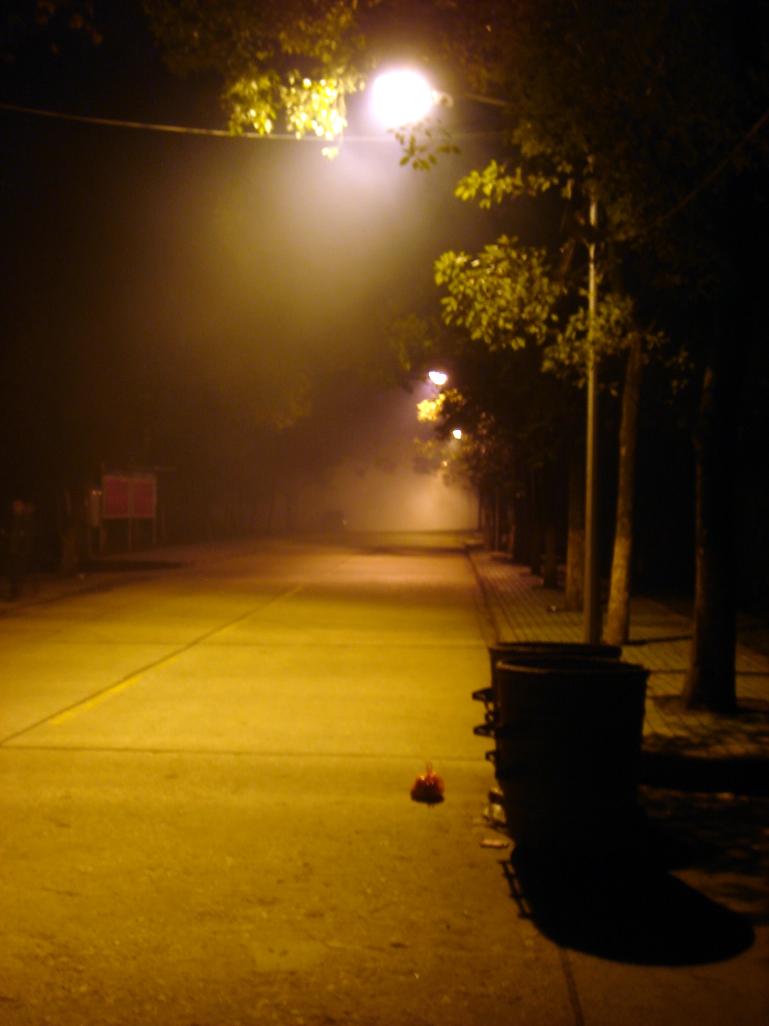 a dark street with some yellow light at night