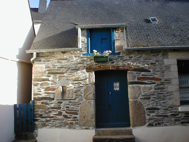 a stone house with blue front door and wooden gate