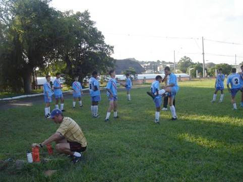 a man crouches in front of a group of young men in soccer uniforms