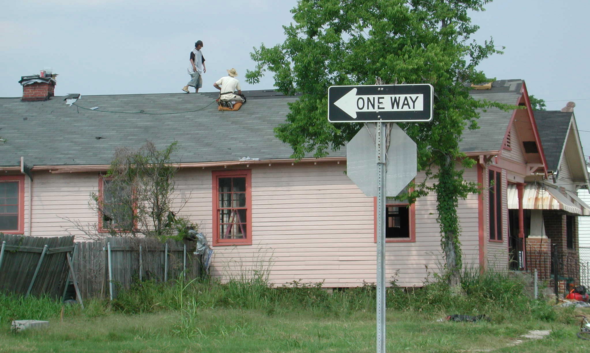 a white street sign in front of a pink house