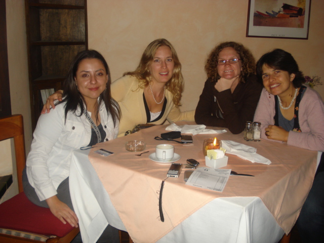 four women sitting at a table smiling for a po