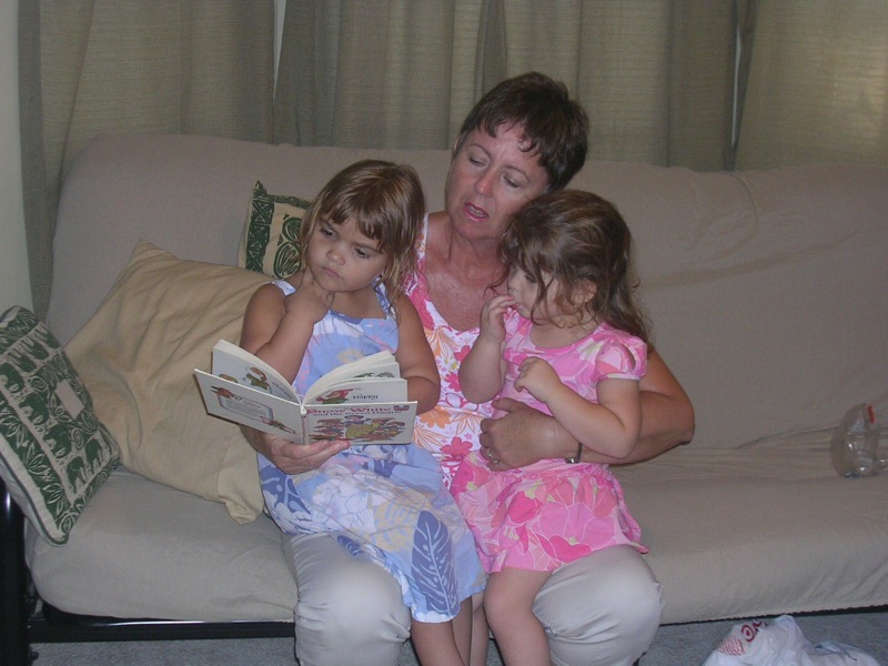 two little girls and an older woman reading a book