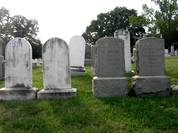 headstones sit in the grass between two graves
