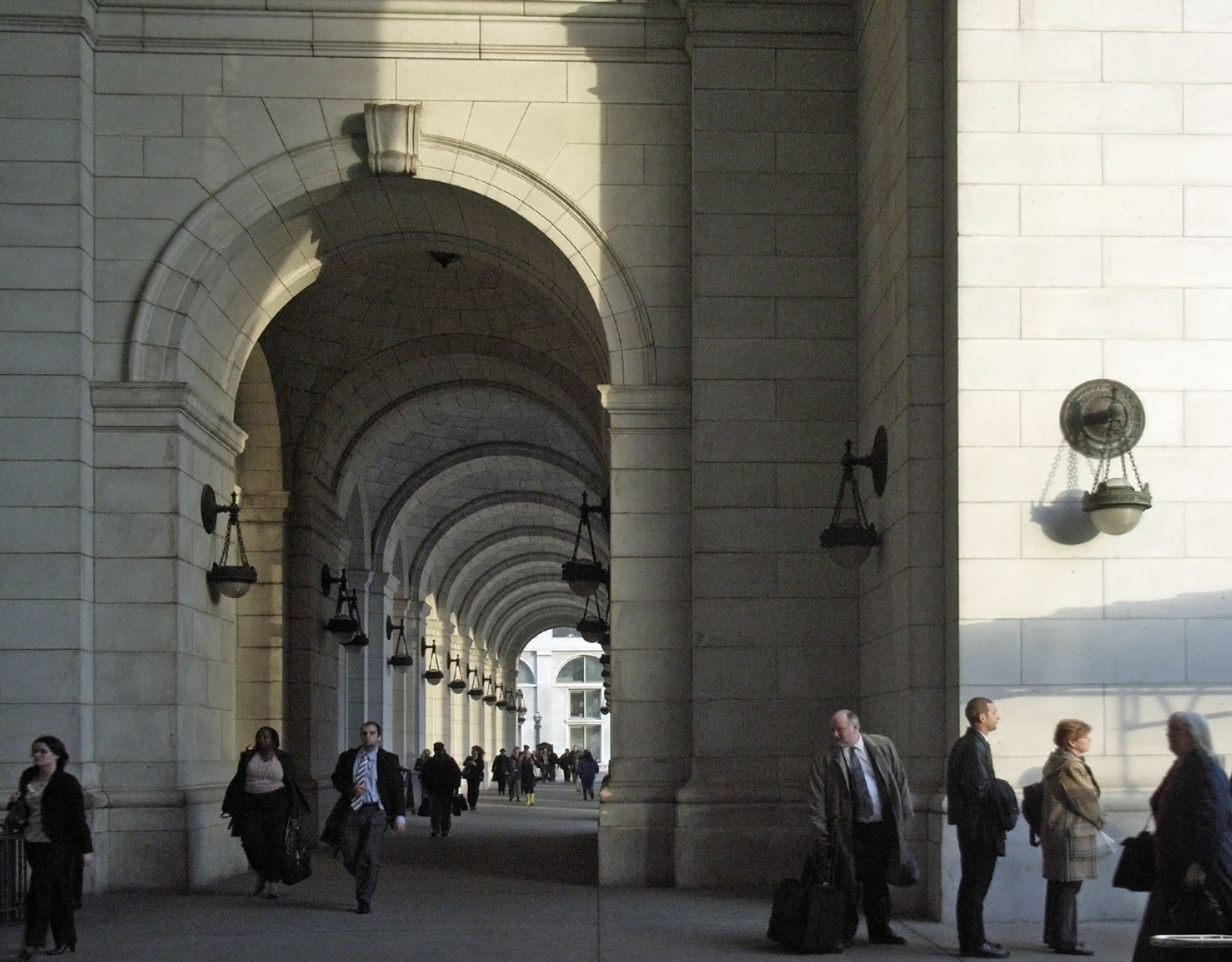 several people are walking down a street with an archway