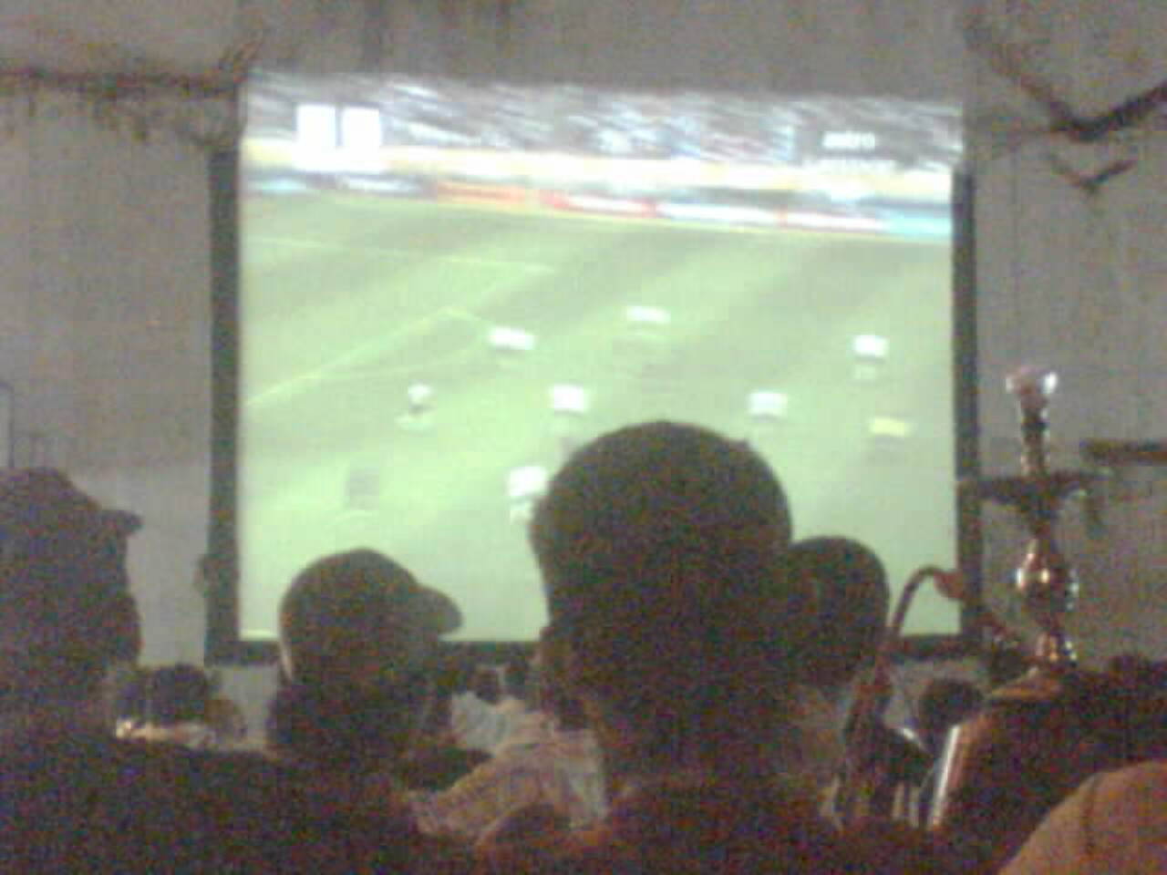 four men watching sports on television in an empty room