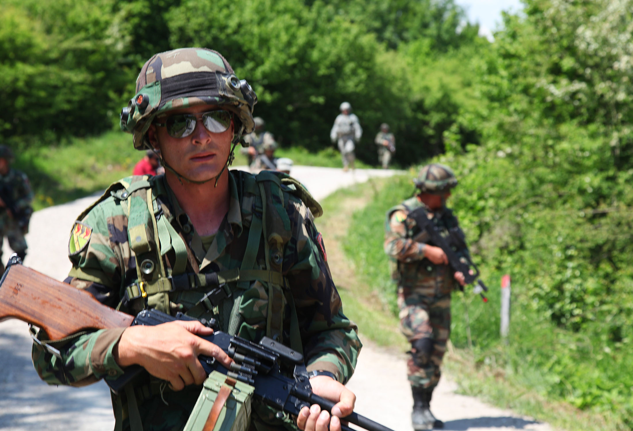 a person in camouflage and sun glasses holding a gun