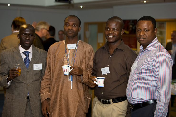 four men are smiling for the camera, one with his id badge on his chest