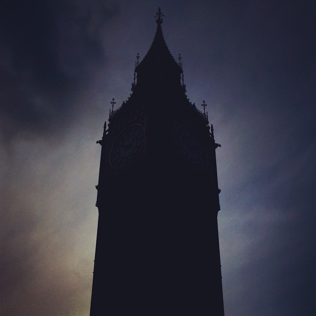 a tall clock tower silhouetted against a dark cloudy sky