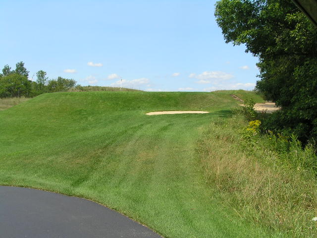 a golf hole sitting on the edge of a dirt road