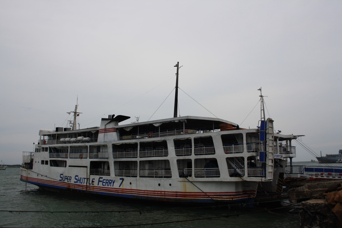 a white, red and blue ferry boat parked on the water