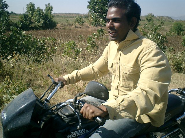 an indian man on a motorcycle smiling