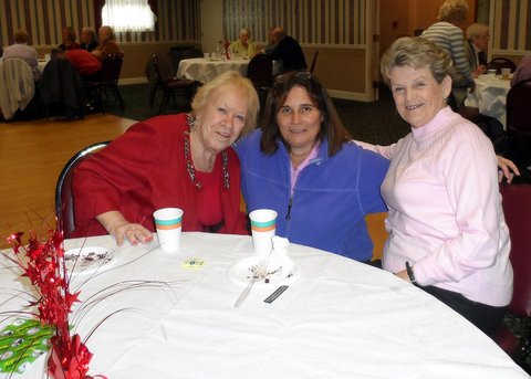 four people pose with cups on top of a table