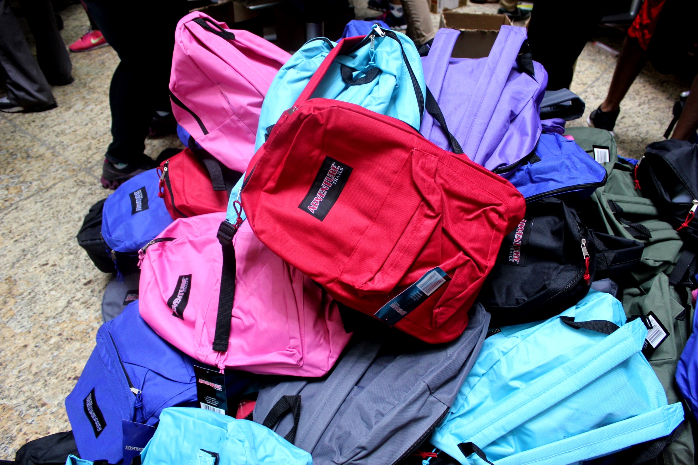 a large pile of various colors backpacks are on the floor