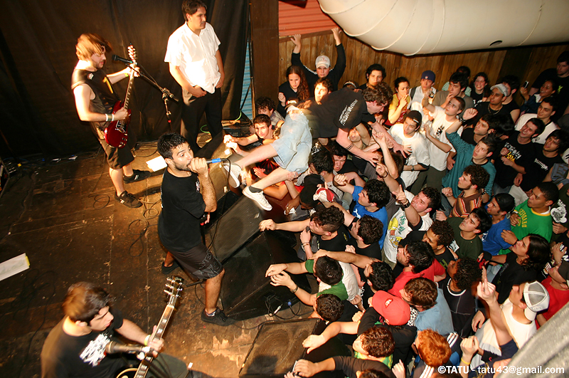 people in front of a large crowd singing and playing guitar