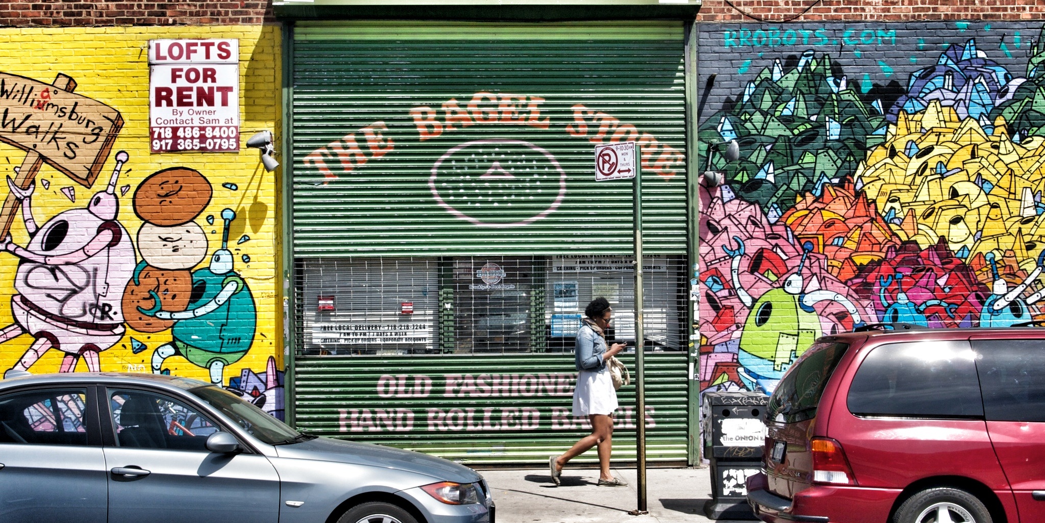 woman walking past a graffiti covered store on a city street